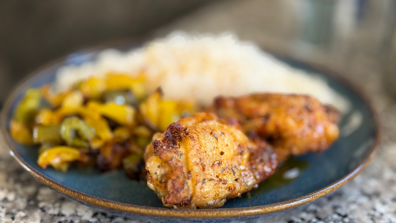 Hauts de cuisses de poulet marinés dorés et poivrons rôtis servis dans une assiette